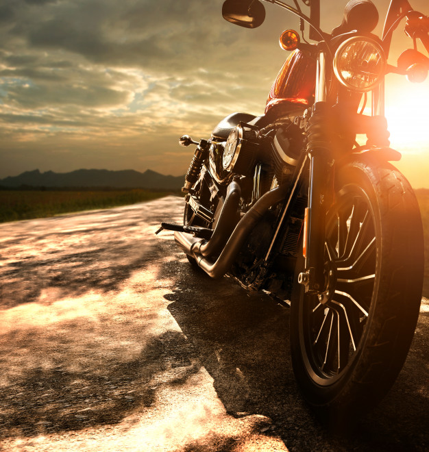 old-retro-motorcycle-traveling-on-country-road-against-beautiful-light-of-sunset-sky_34013-284